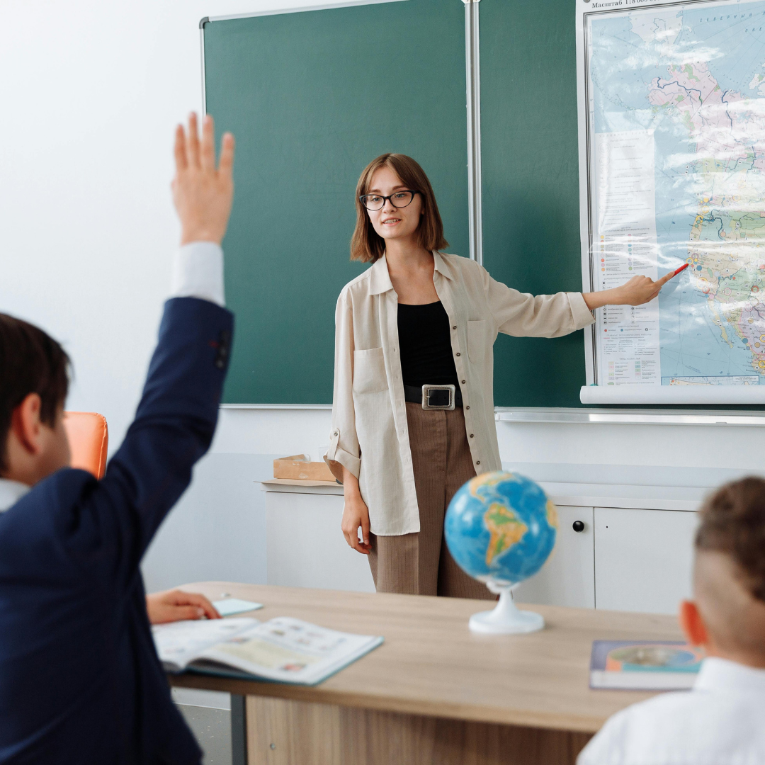 A teacher with students pointing to a map